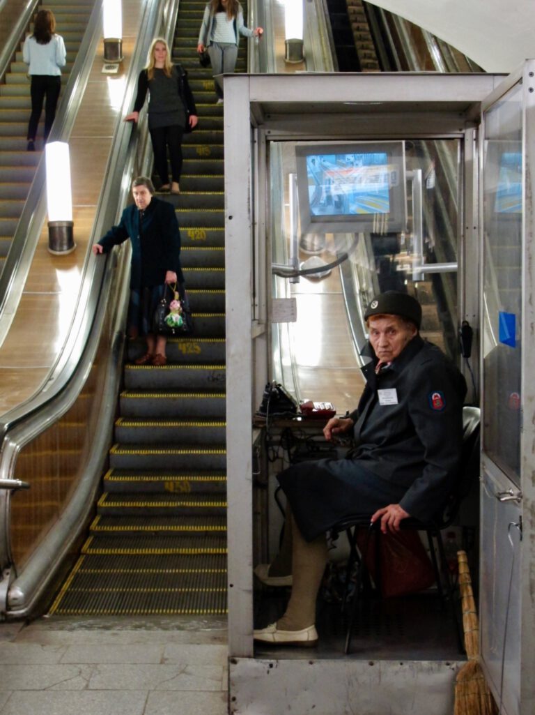 Mitarbeiterin der Moskauer Metro in einem Glaskasten neben einer Rolltreppe