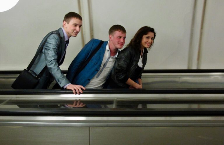 Drei junge Fahrgäste auf einer Rolltreppe in einer Moskauer Metrostation
